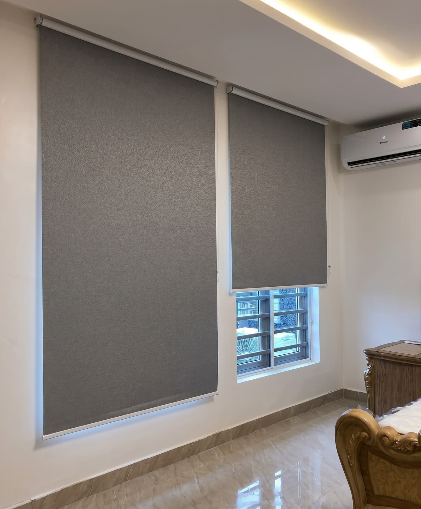 Grey blackout roller blinds in a finished bedroom with cove lighting